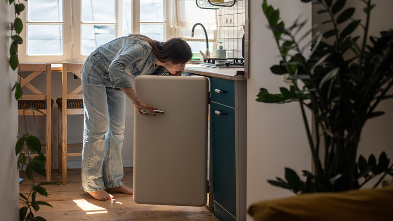 woman opening mini fridge