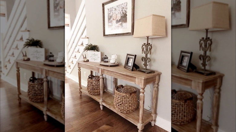 A farmhouse-style console table with two woven baskets underneath concealing an air vent