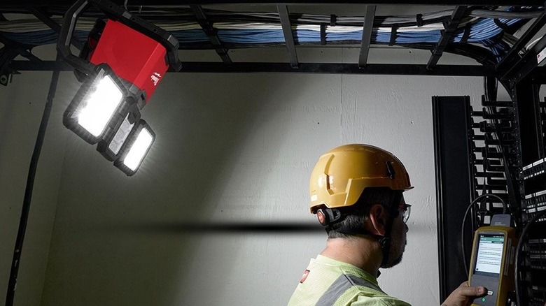 Man working in a dark area with a three-panel LED light