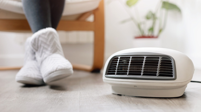 Person sitting with slippered feet near a space heater