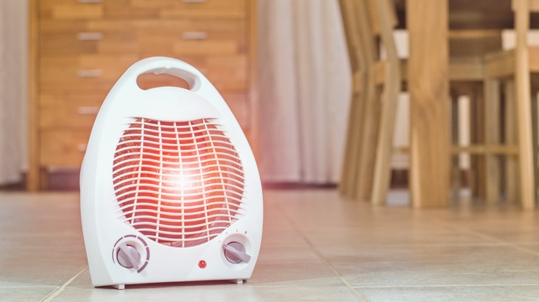 A powered space heater on the floor near a dining table