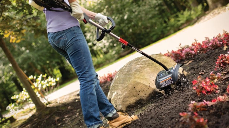 Woman using garden cultivator attachment