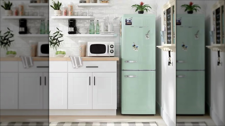 A mint green retro-look refrigerator stands in a bright white kitchen