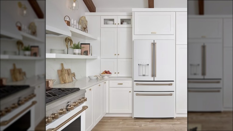 A white Cafe refrigerator with gold handles is displayed in an elegant all-white kitchen