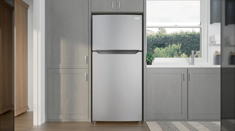 A small Frigidaire top-freezer refrigerator is shown in a grey kitchen