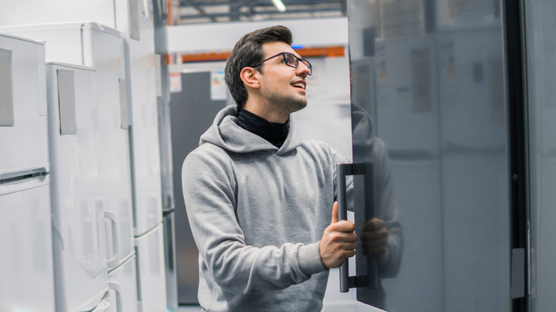 A smiling man looks at a refrigerator on display