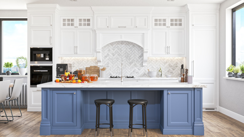 Stylish kitchen white white cabinets and a blue island.