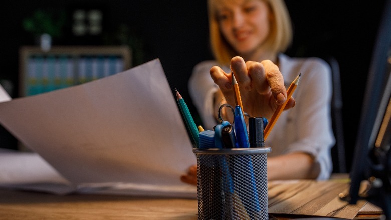 Woman reaching for pencil in holder