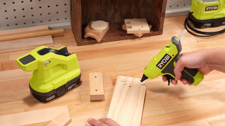 A person gluing wood with a Ryobi One+ compact glue gun