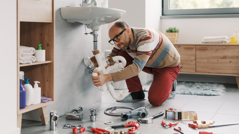 Man beneath a sink doing DIY plumbing