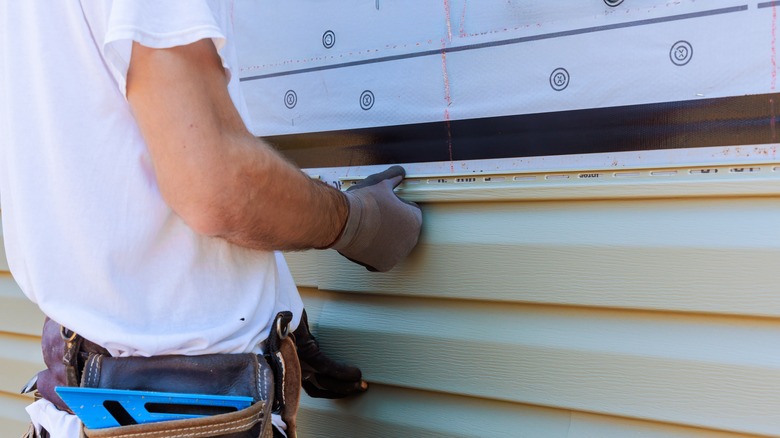 Handyman installing house siding.