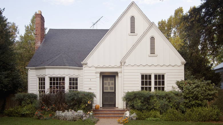 Exterior of white and gray home surrounded by hedges.