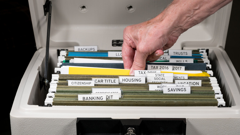 Hand touching documents in well-organized fireproof safe with file folders