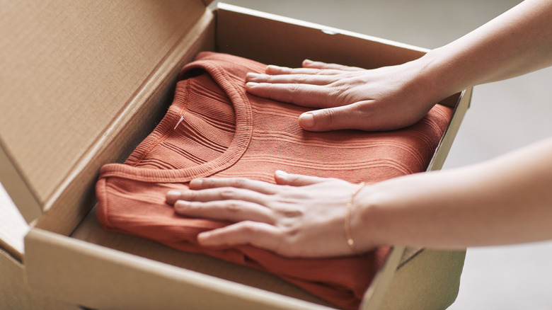 hands pressing a sweater into a box