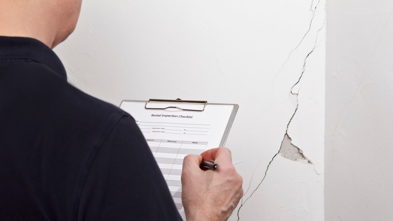 Man inspecting crack in house 