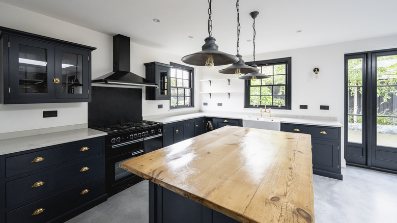 Kitchen with black cabinets, granite countertops, kitchen island, and pendant lights