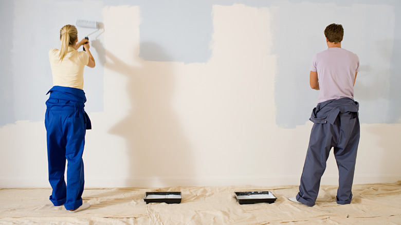 Man and woman painting a white wall in a pastel blue shade