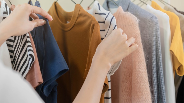 person looking at hanging clothes 