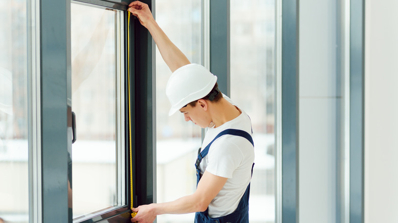 Construction worker measuring windows