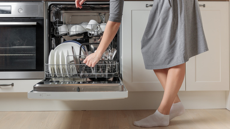 Someone adding dishes to their dishwasher