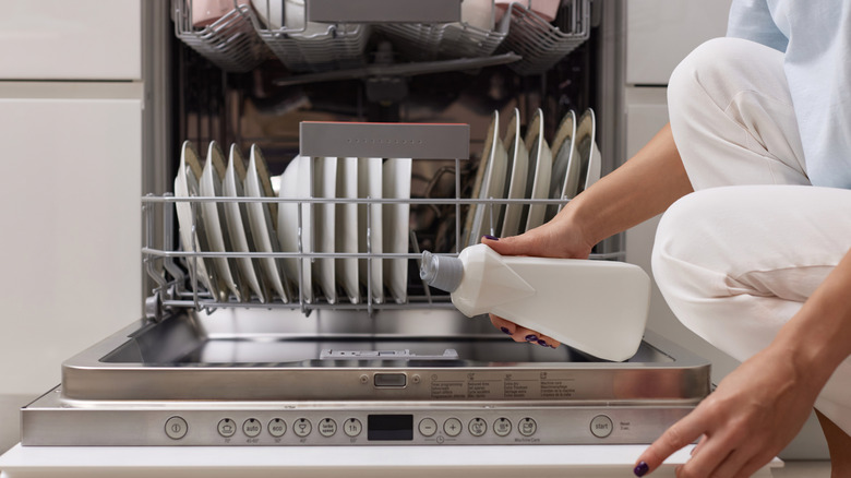 A person pours liquid into dishwasher