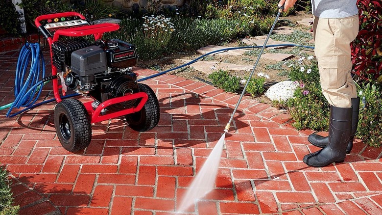 A person is power washing a walkway