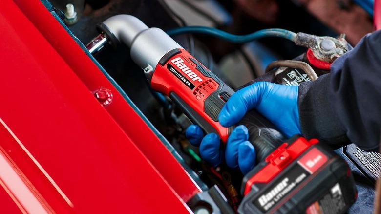 A person is using an impact wrench to fix a car