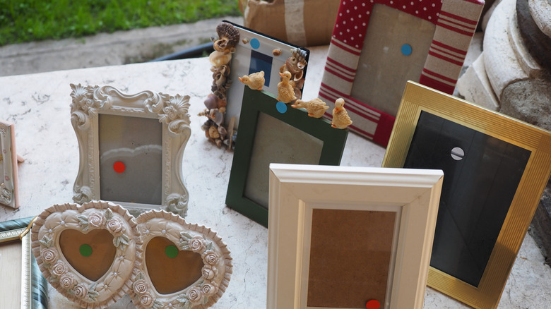 Assorted empty picture frames on a table at an outdoor market.