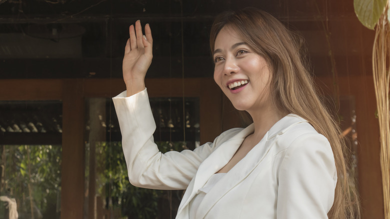 woman in white coat waving 