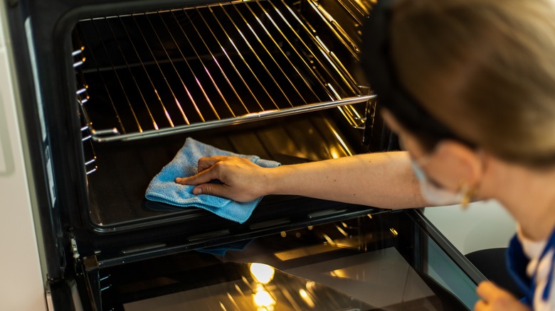 person cleaning oven