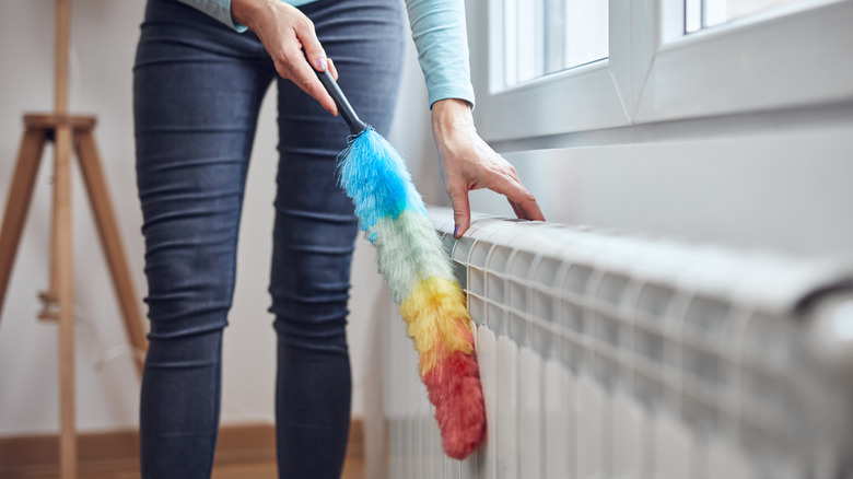 person dusting radiator