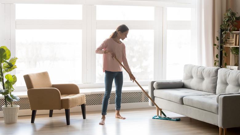 person smiling and mopping floor