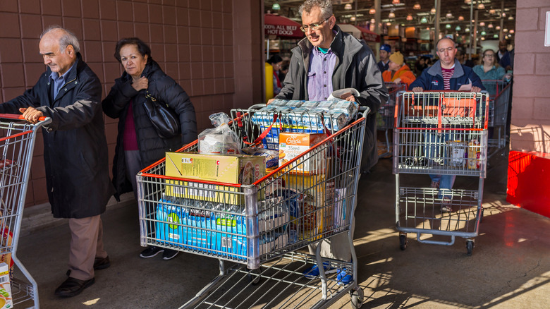 Shoppers exit a store with full carts