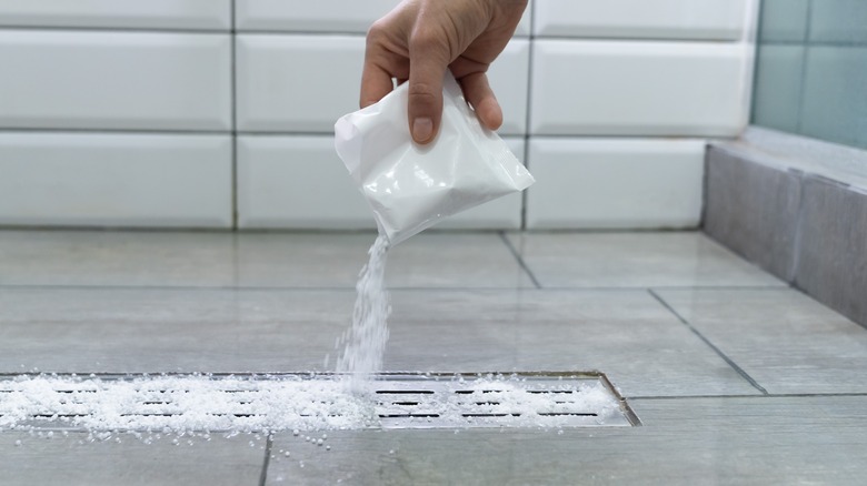 Hand pouring salt on drain