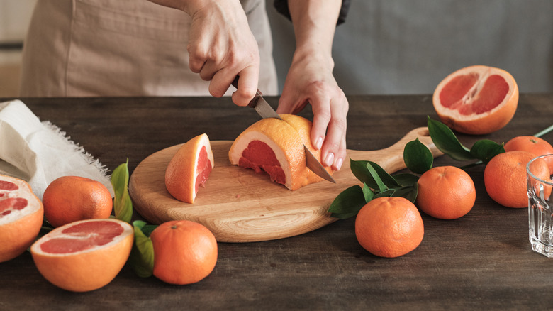 person slicing a grapefruit