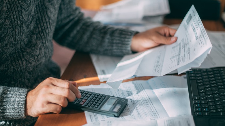 Person calculating bills at desk