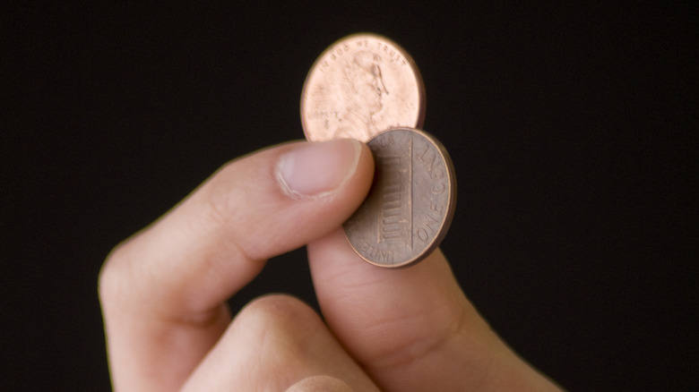 hand holding two pennies