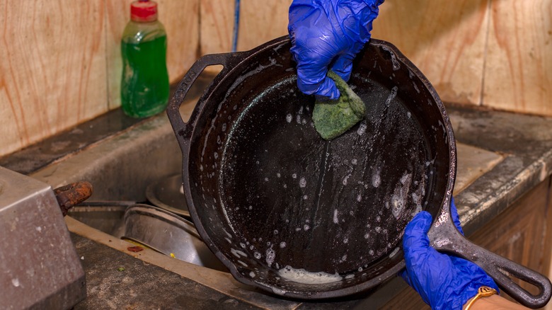 Person scrubbing cast iron pan