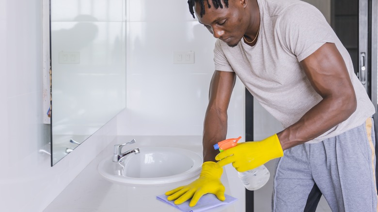 Person disinfecting bathroom counter