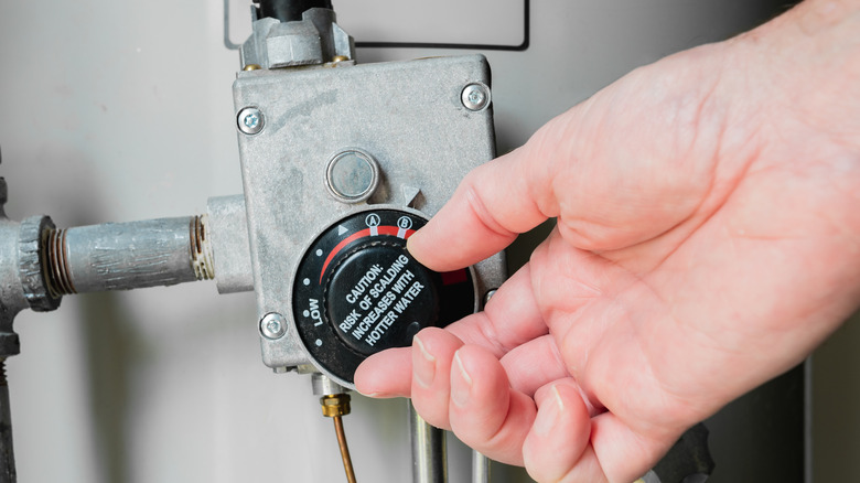 Person adjusting hot water tank