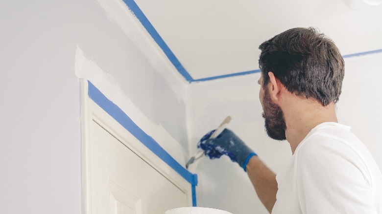 Man painting interior house trim 