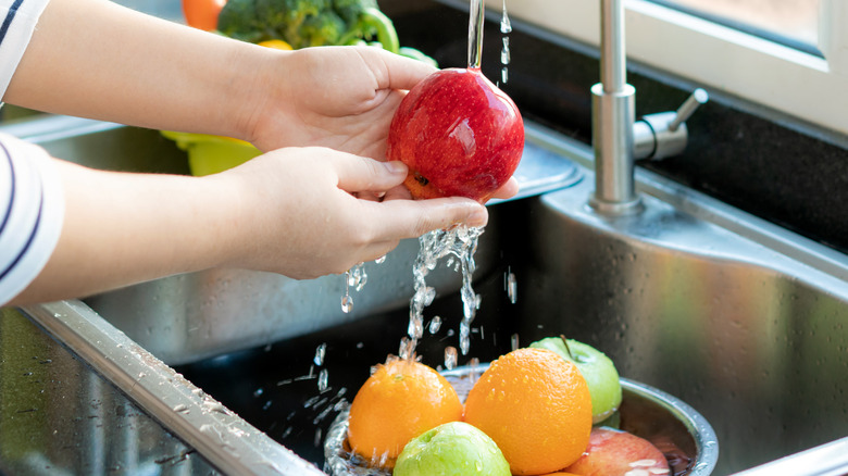 Person washing apple in sink