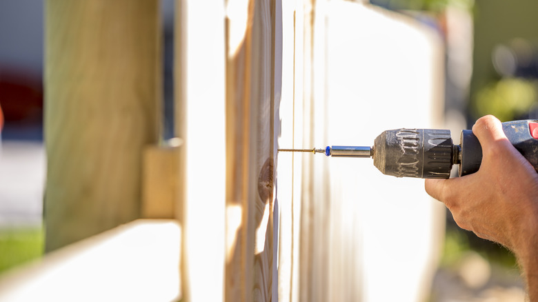 Man building a fence with a drill