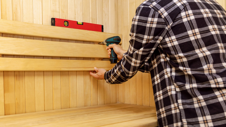 Person installing sauna bench with drill