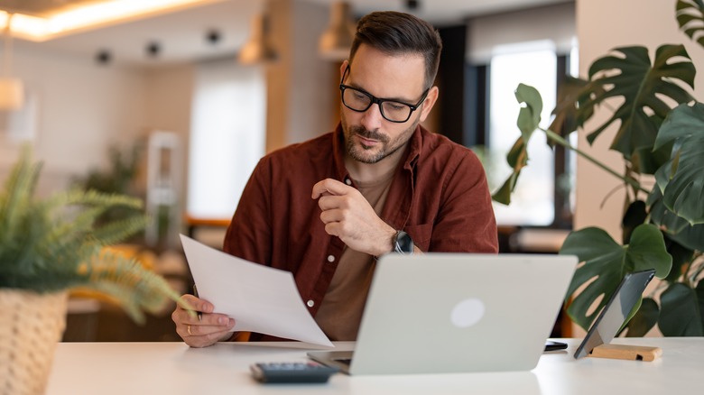 Man working on laptop and calculator