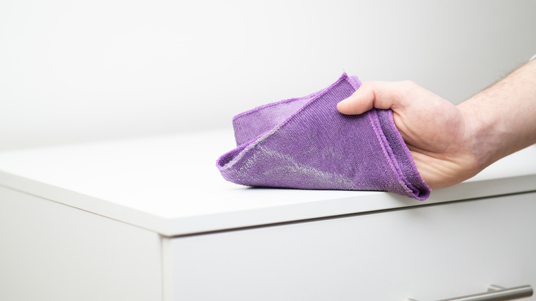 A person wiping down a storage unit with a purple microfiber towel