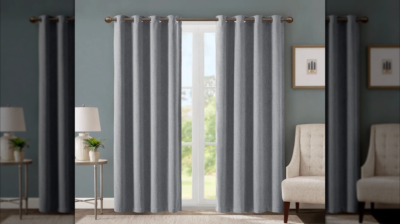 A pair of grey blackout curtains hang in a light blue room