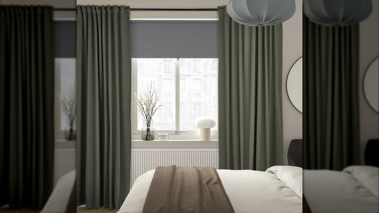 Dark green blackout curtains hang in a neutral bedroom