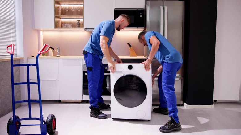 Two men installing a washing machine