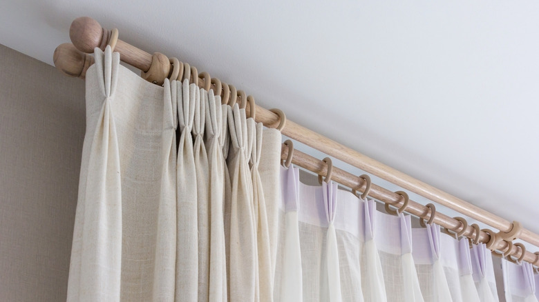 Curtains hung close to a ceiling in a modern window frame.